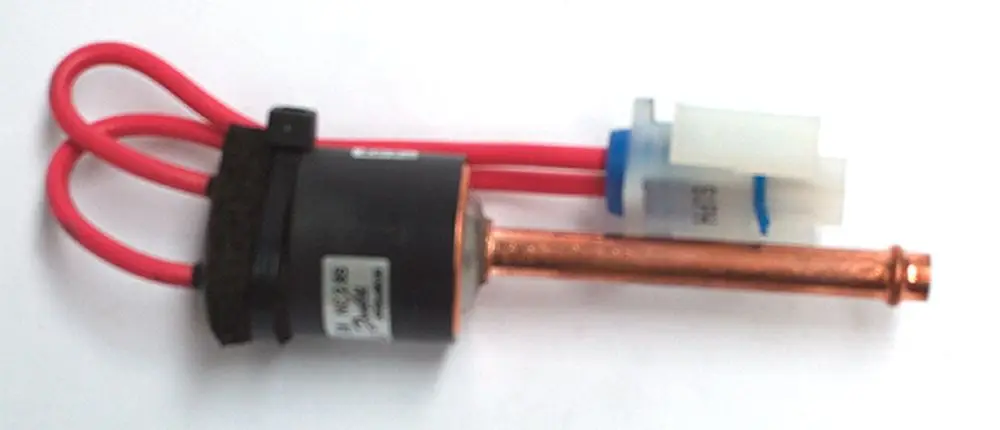 Druckschalter von Daikin mit zwei roten Anschlusskabeln und einem Kupferrohr. Der Schalter ist kompakt und für technische Anwendungen konzipiert.